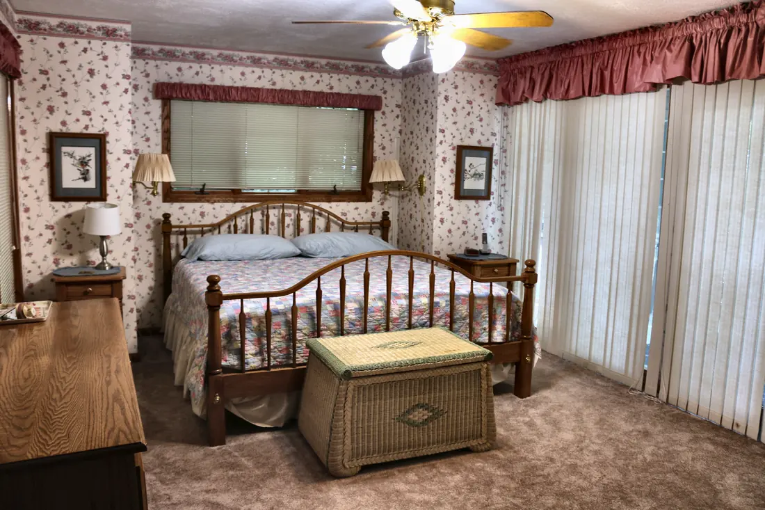 Main-floor king bedroom with spindle bed, patchwork quilt and wicker chest