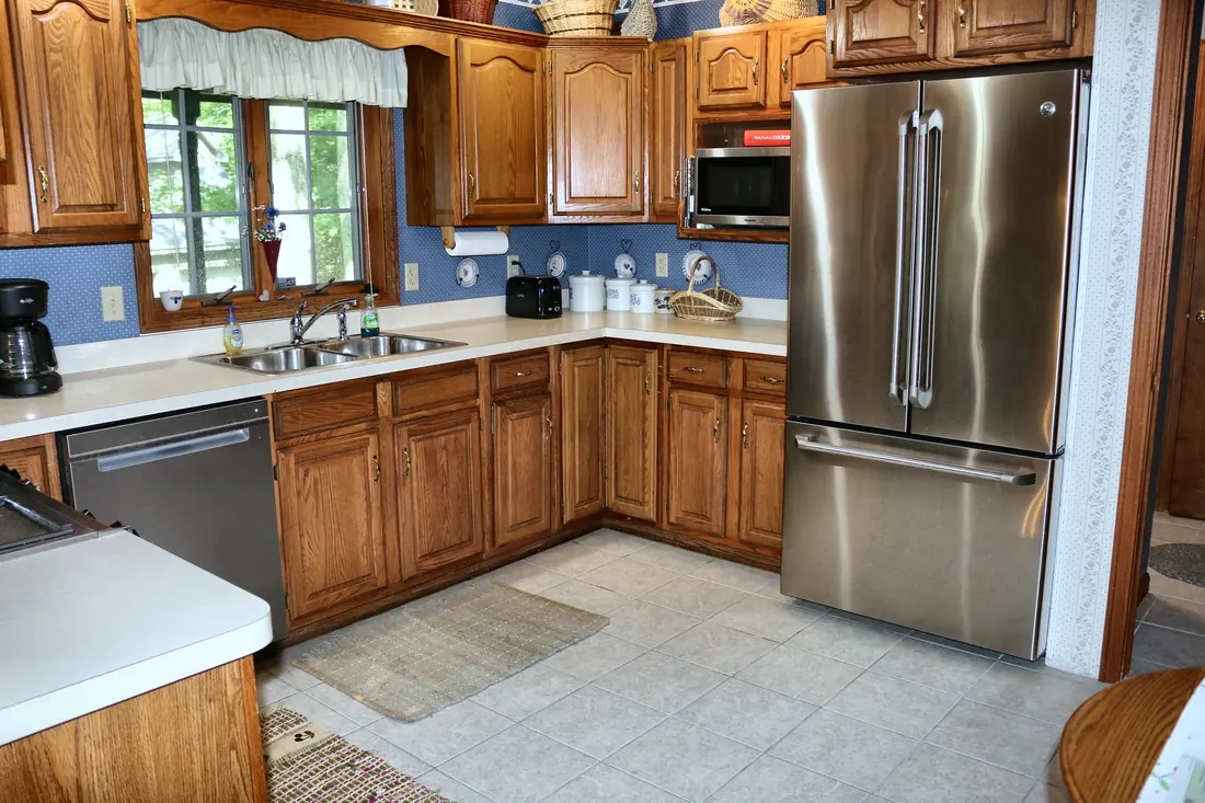 Oak kitchen with a stainless French-door refrigerator, dishwasher, double sink and garden window